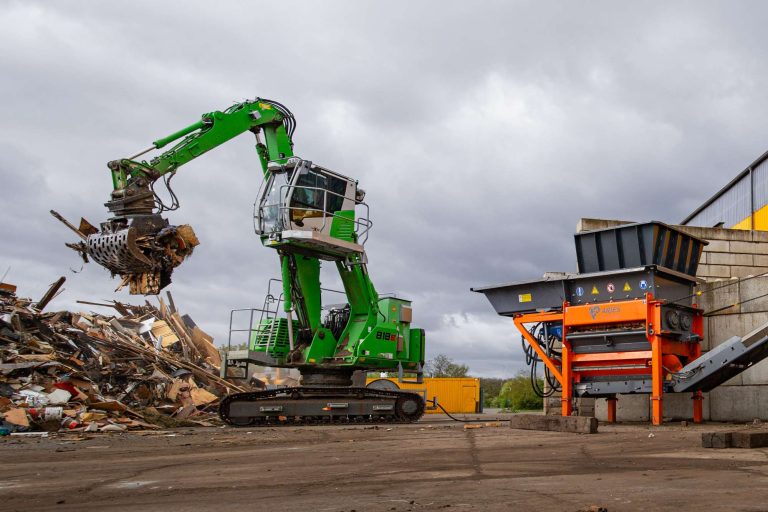 Bagger bestückt Zerkleinerungsanlage von ARJES mit Altholz