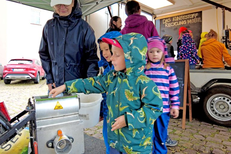 Recyclingfähige Plastikteilchen werden von den Lindenzwergen der Kita Dorndorf in den Häcksler des Recycling-Fahrrads gefüllt