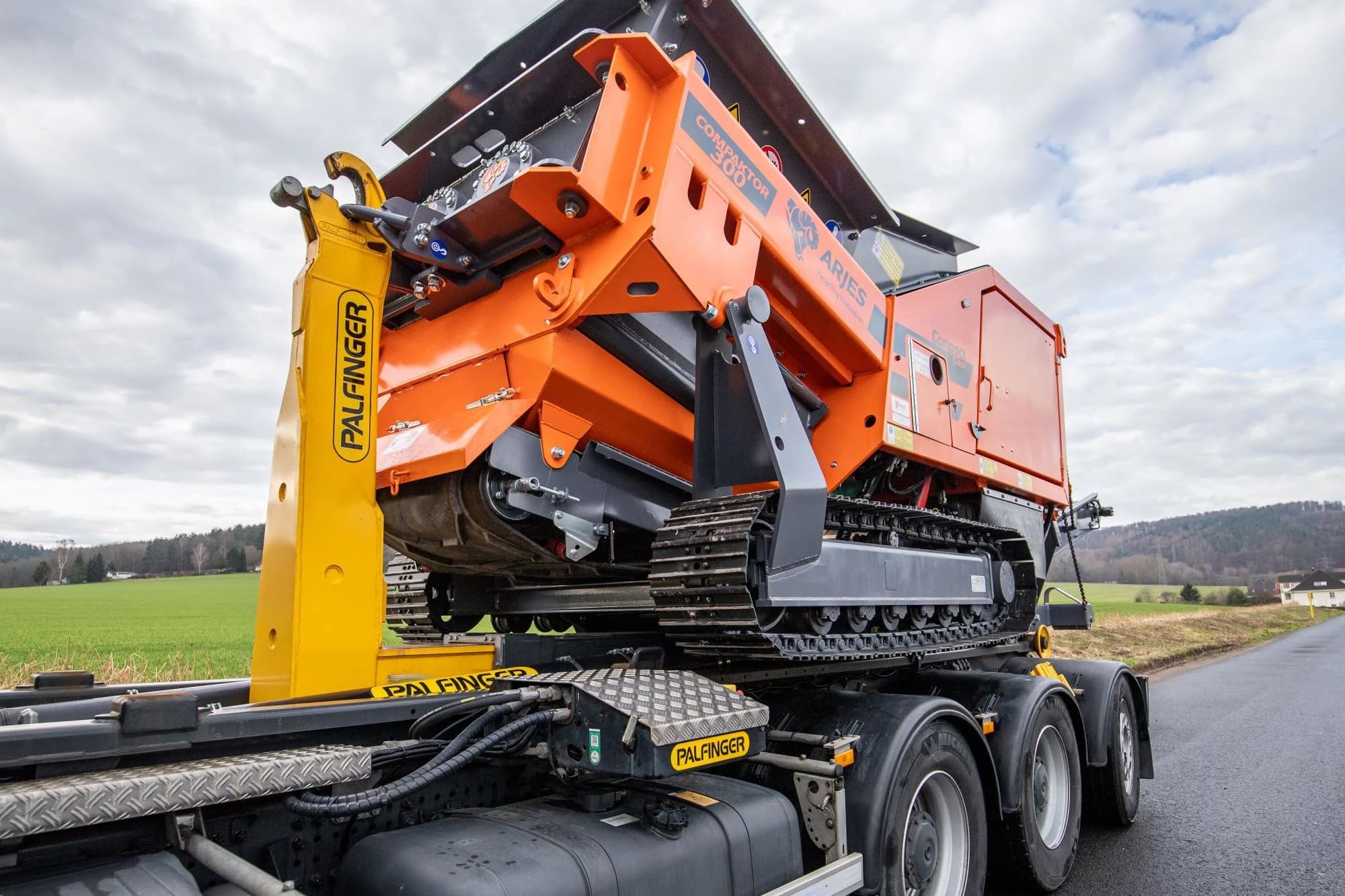 ARJES COMPAKTOR 300 being loaded onto a truck using a hook-lift system